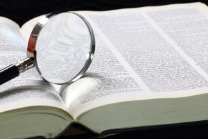 Dictionary with an magnifying glass on top